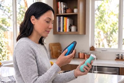 a woman comparing two Kegel trainers in a kitchen