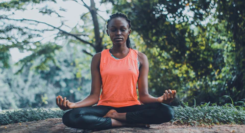 a woman sitting in a lotus position in a park