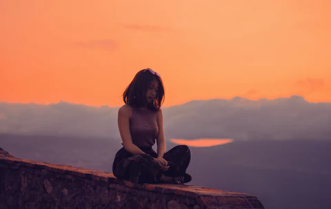 a woman sitting on top of a stone wall