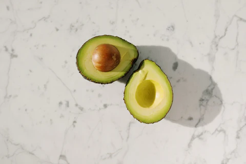an avocado cut in half on a marble surface