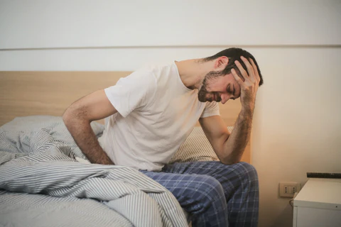 a man sitting on a bed with his head in his hands