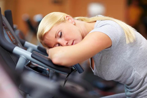 a woman resting her head on a stationary exercise bike