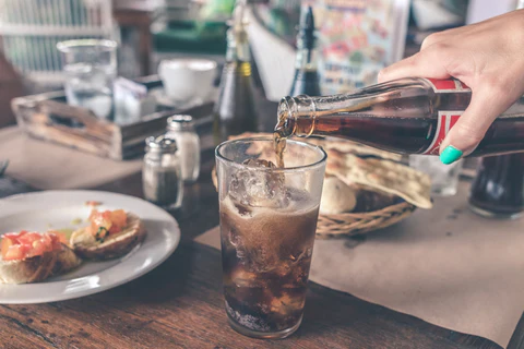 a person pouring a beverage into a glass
