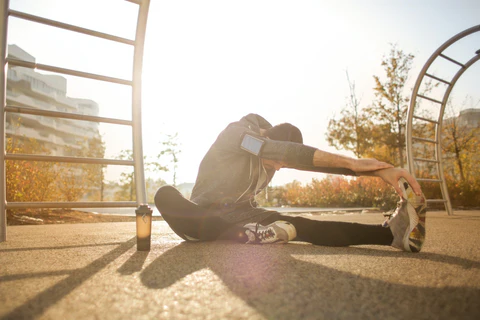 a man sitting on the ground next to a metal ladder