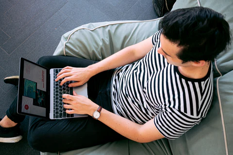 a woman sitting on a couch using a laptop computer