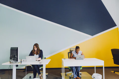 a couple of people sitting at a table with laptops