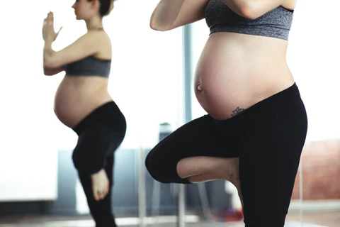 a pregnant woman doing yoga in front of a mirror