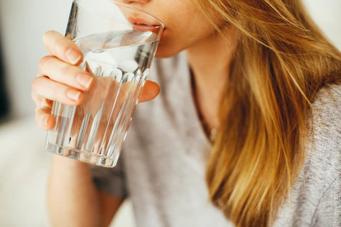 a woman drinking from a glass of water
