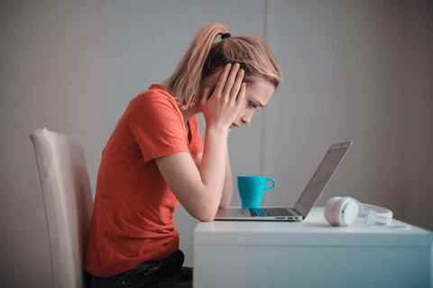 What is hypotonic pelvic floor dysfunction A woman sitting at a desk with a laptop, holding her head in her hands