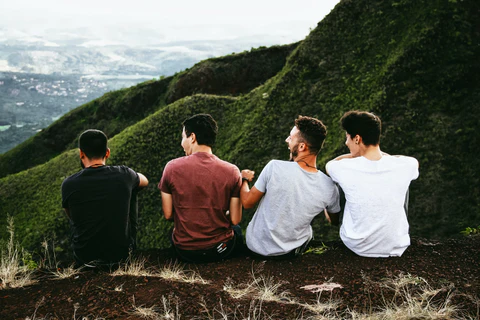 a group of men sitting on top of a lush green hillside