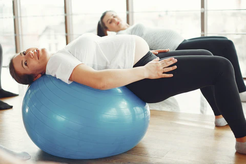 a woman is laying on an exercise ball
