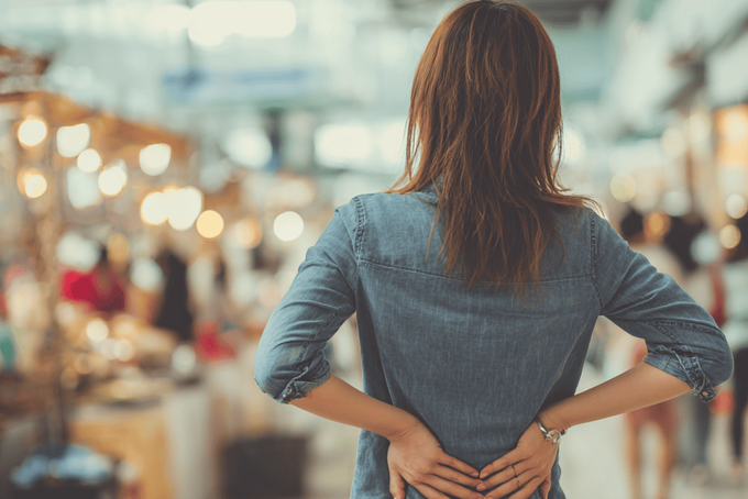 Hypertonic Pelvic Floor: 5 Most Common Causes & When to Worry A woman holding onto her back.