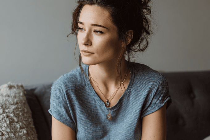 Why I Pee When I Sneeze: Causes, Fixes, and Expert Guidance A woman sitting on a couch who has leakage when she sneezes.