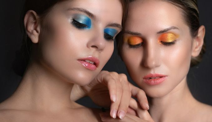 two beautiful women with metallic and shimmery eye makeup posing for a picture