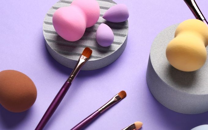 A purple table topped with makeup brushes and sponges