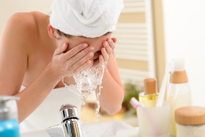 A woman cleansing her face to get ahead of maturing skin issues like enlarged pores, fine lines, etc