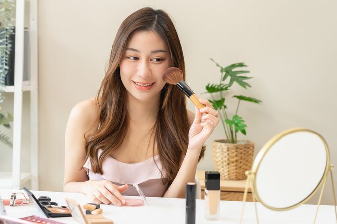 A woman holding a brush over her face.