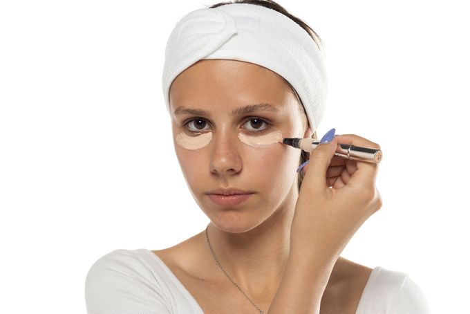 A woman applying the right shade of concealer to her cheek.