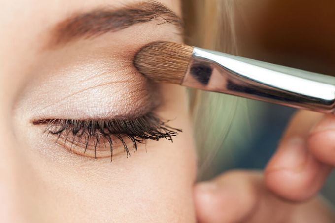 A woman applying eyeshadow for green eyes.