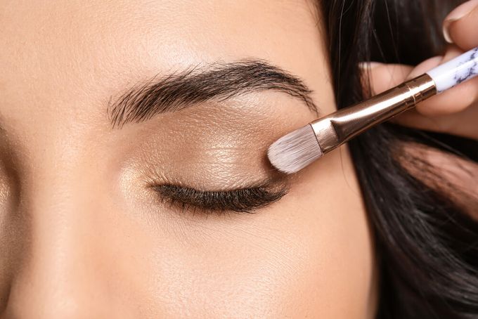 A woman applying makeup with an eyeshadow brush