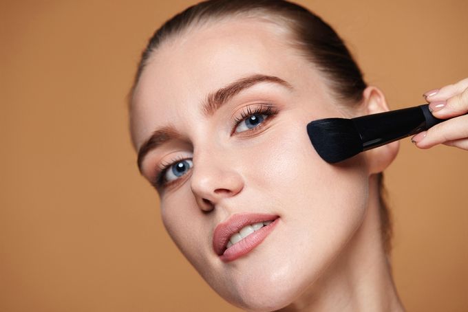 A woman using a brush on her face.