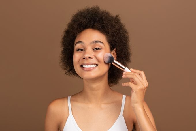 A woman holding a brush to her face.