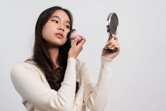 A woman holding a mirror and a brush in her hand.