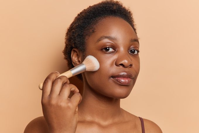 A woman brushes her face with a brush