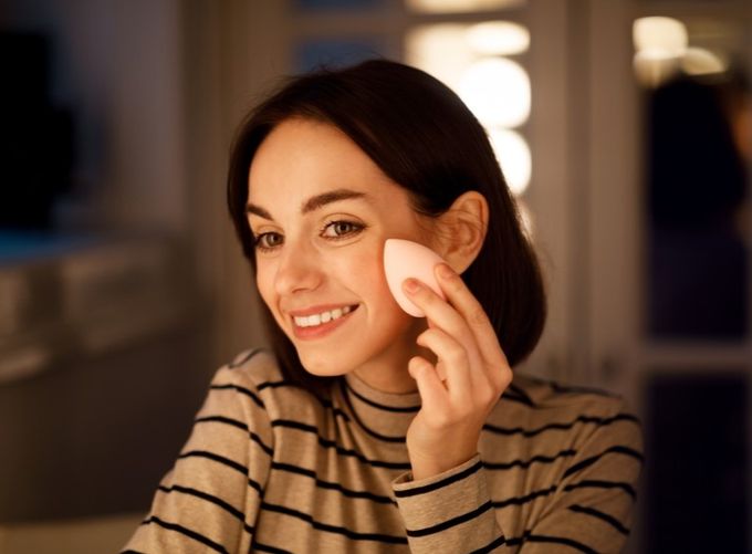 A woman smiles as she holds an object in her hand.