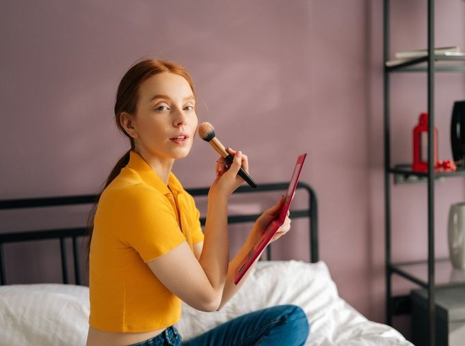 A woman sitting on a bed with a brush in her hand.