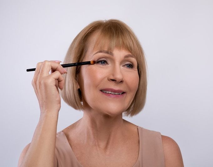 A woman holding a brush to her eye.