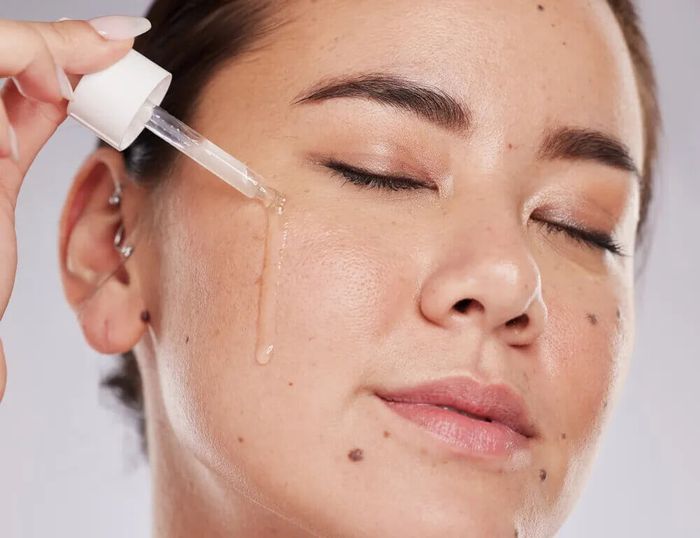 A woman applying a serum to her face as part of her winter skincare  regimen