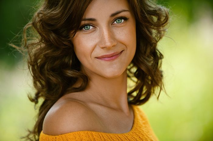 A close up of a green-eyed woman wearing eyeshadow.