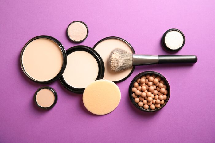 A set of makeup powder products on a purple background