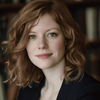 a close up of a person with a book shelf in the background