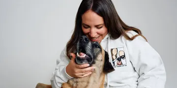 a woman holding a dog and smiling at the camera