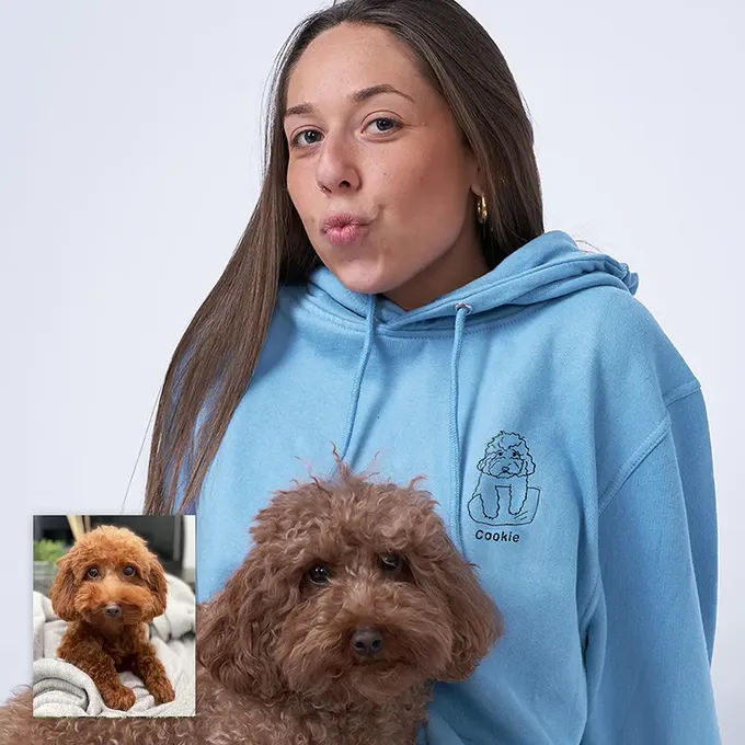 a woman in a blue hoodie holding a brown dog