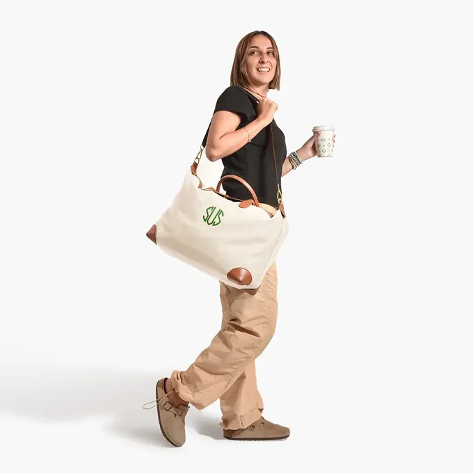 a woman is carrying a bag and a cup