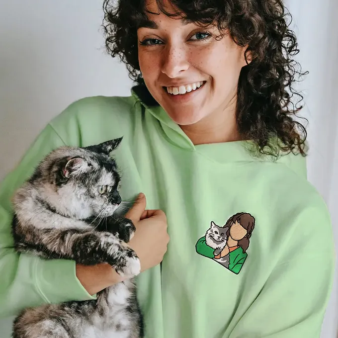 a woman in a green hoodie holding a cat