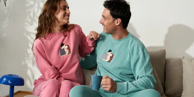 a man and woman sitting on a couch in matching pajamas
