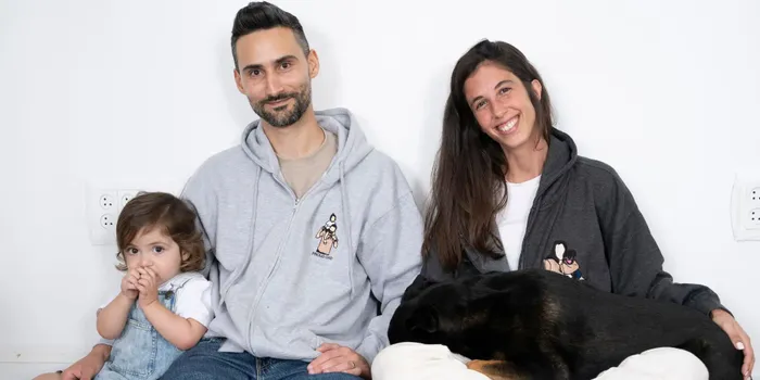 a man and woman sitting next to a baby and a dog