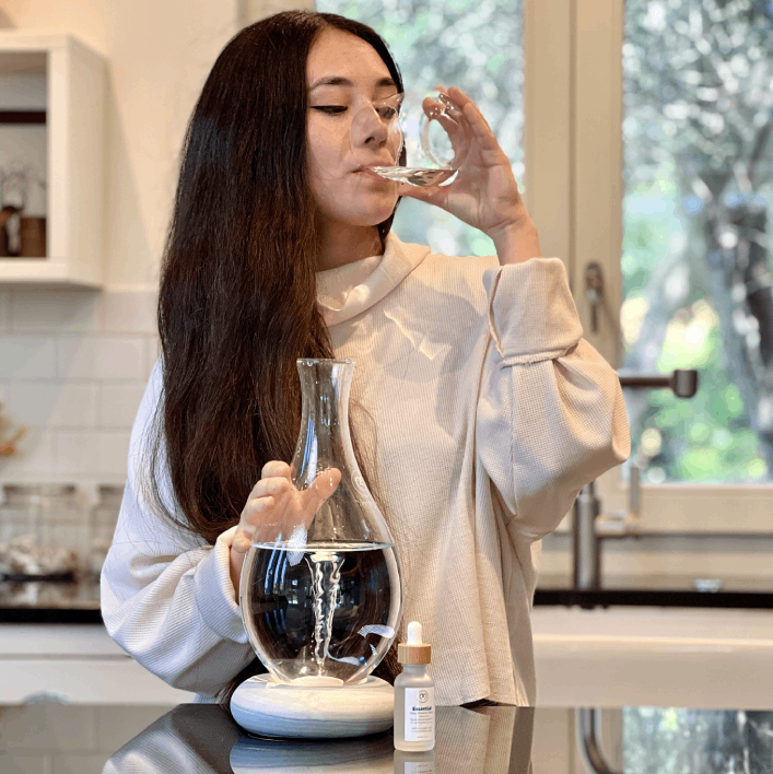 Girl drinking water from Mayu Swirl water structuring carafe.