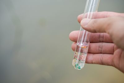 A close-up shot of a test tube, with magnified microplastics visible inside.
