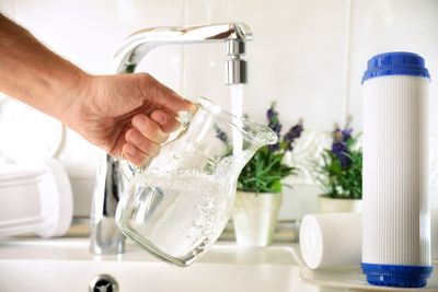 Man pouring water into a glass jug from a tap with an RO filter