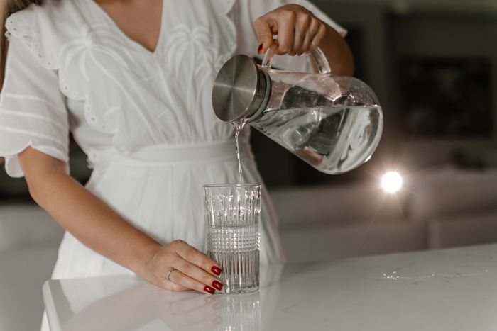 Woman pouring water from a glass jug into a glass