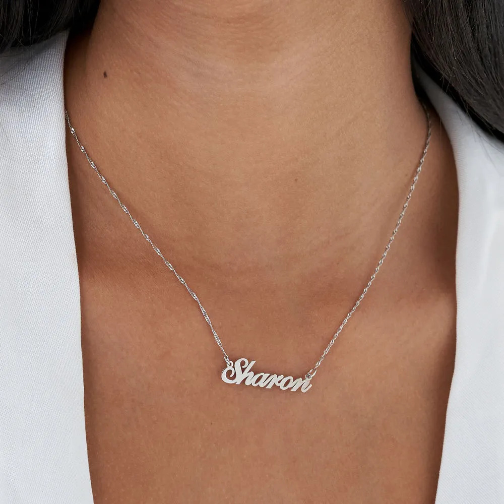 Woman wearing a white gold necklace around her neck with a name pendant