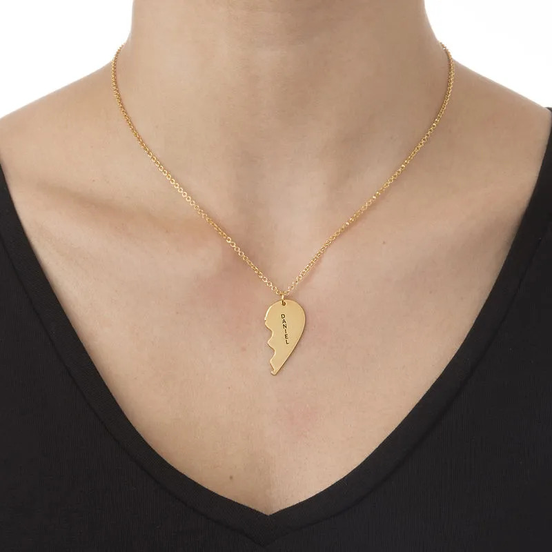 Woman wearing a gold plated necklace with an inscribed broken-heart shaped pendant 