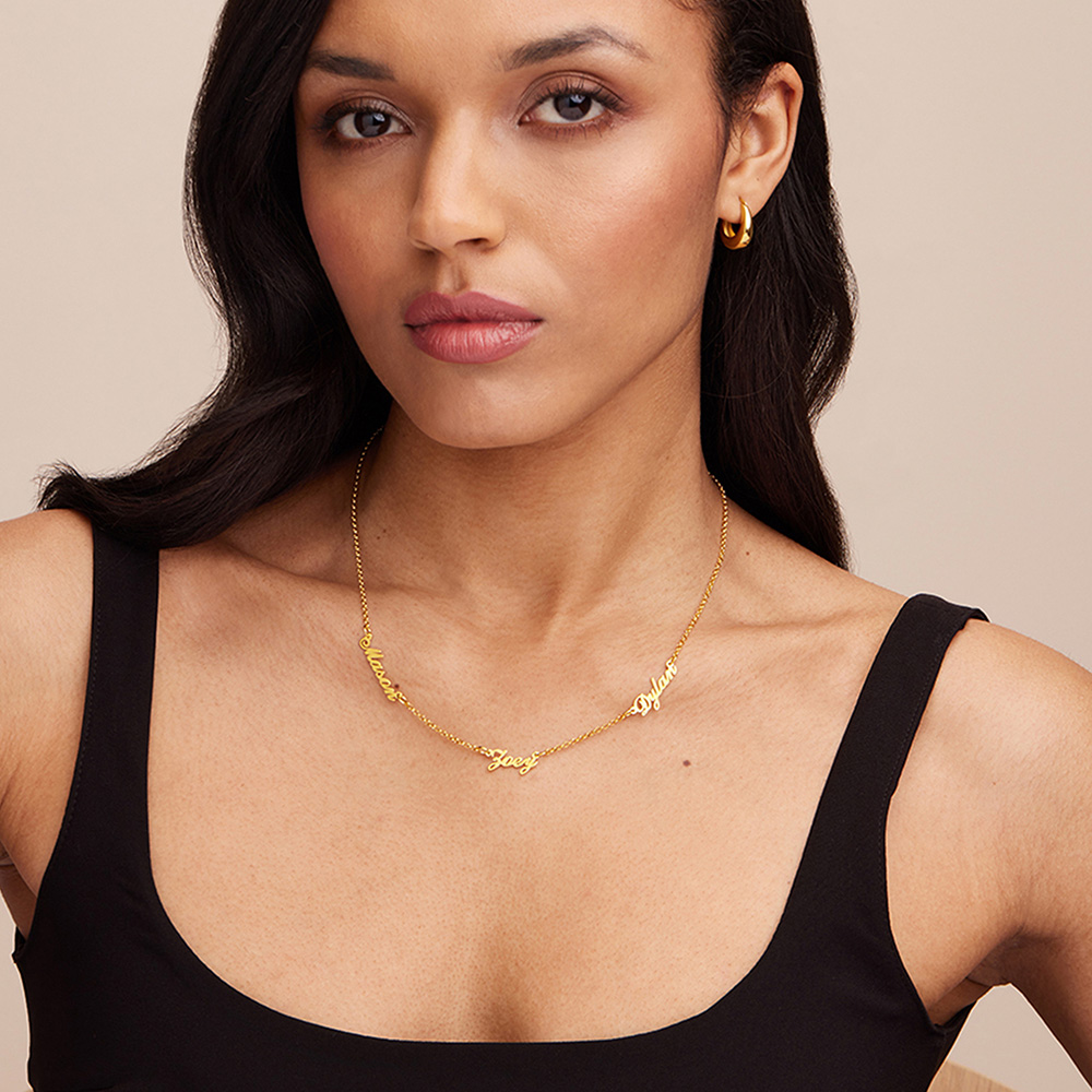 a woman wearing a black top and a gold necklace