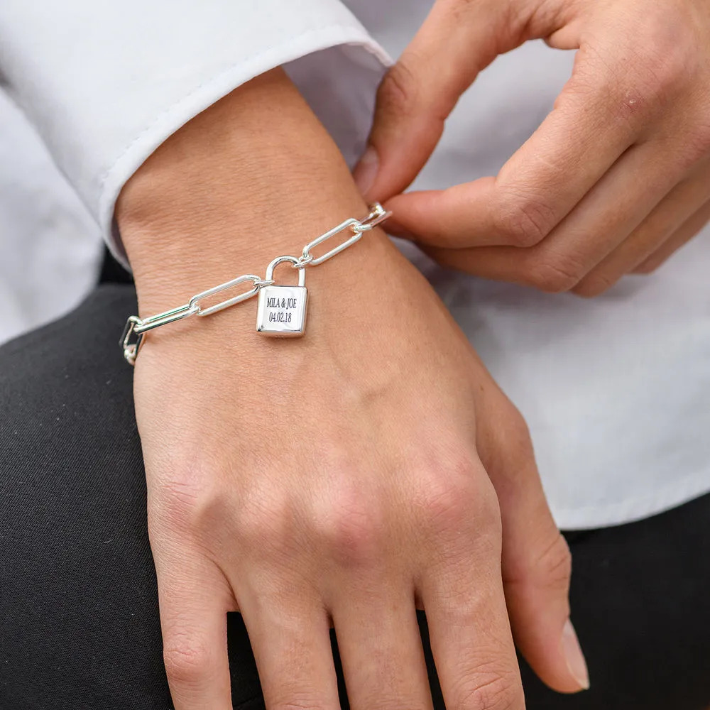 Woman wearing sterling silver chain link bracelet with an engraved  padlock charm 