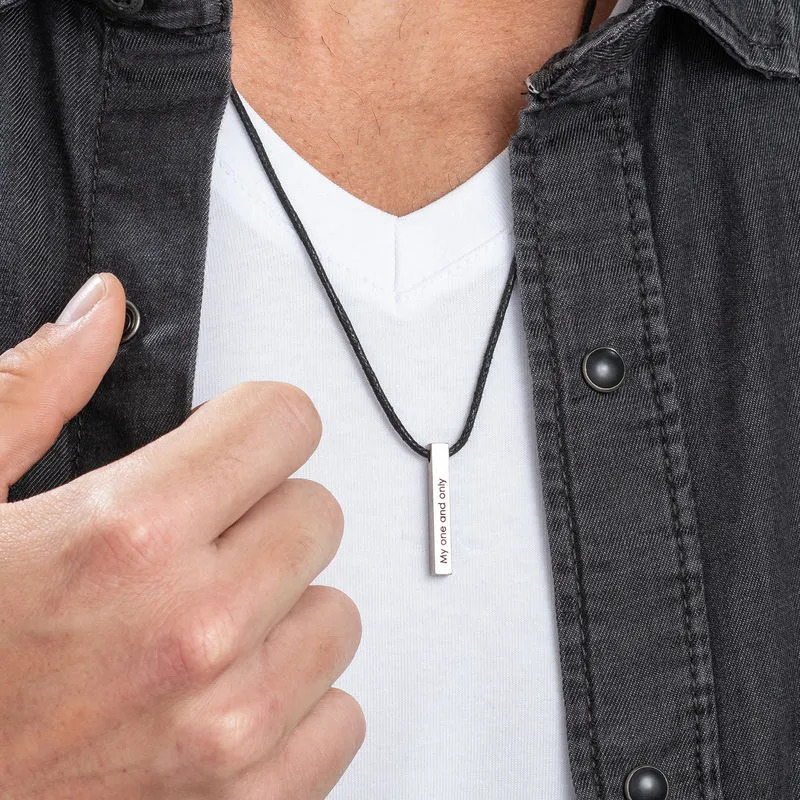A man wearing a sterling silver vertical bar necklace with a thin black rope string 